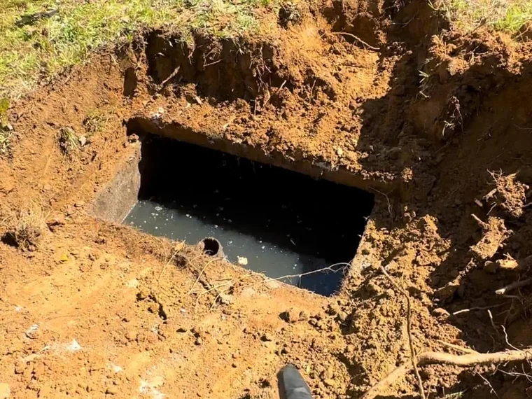 Exposed concrete septic tank with inlet uncovered during a septic inspection