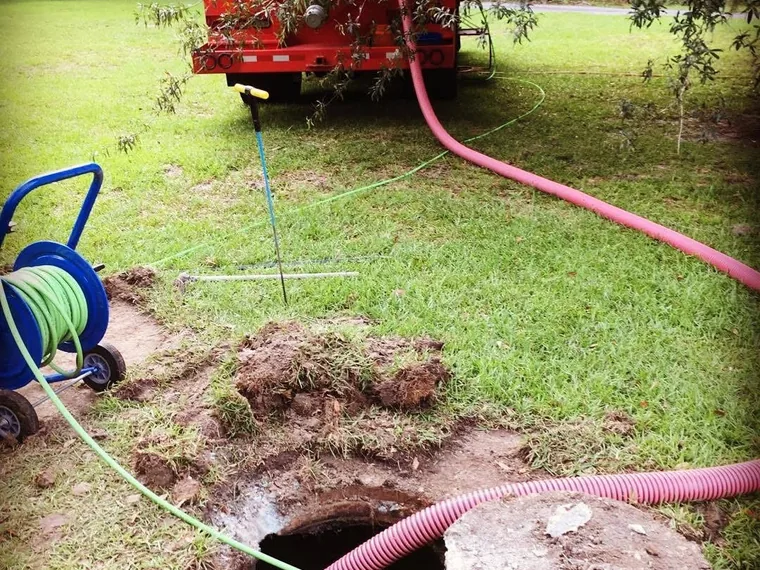 SepticRooter vacuum truck with a hose running into an opened septic tank