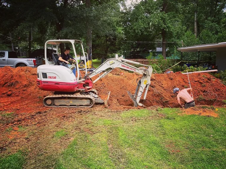 SepticRooter excavator digging to a septic system for repair